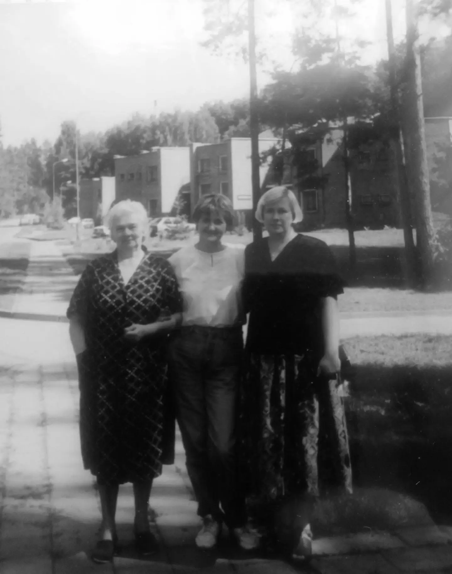 Three women standing outside the building in a historical photograph.
